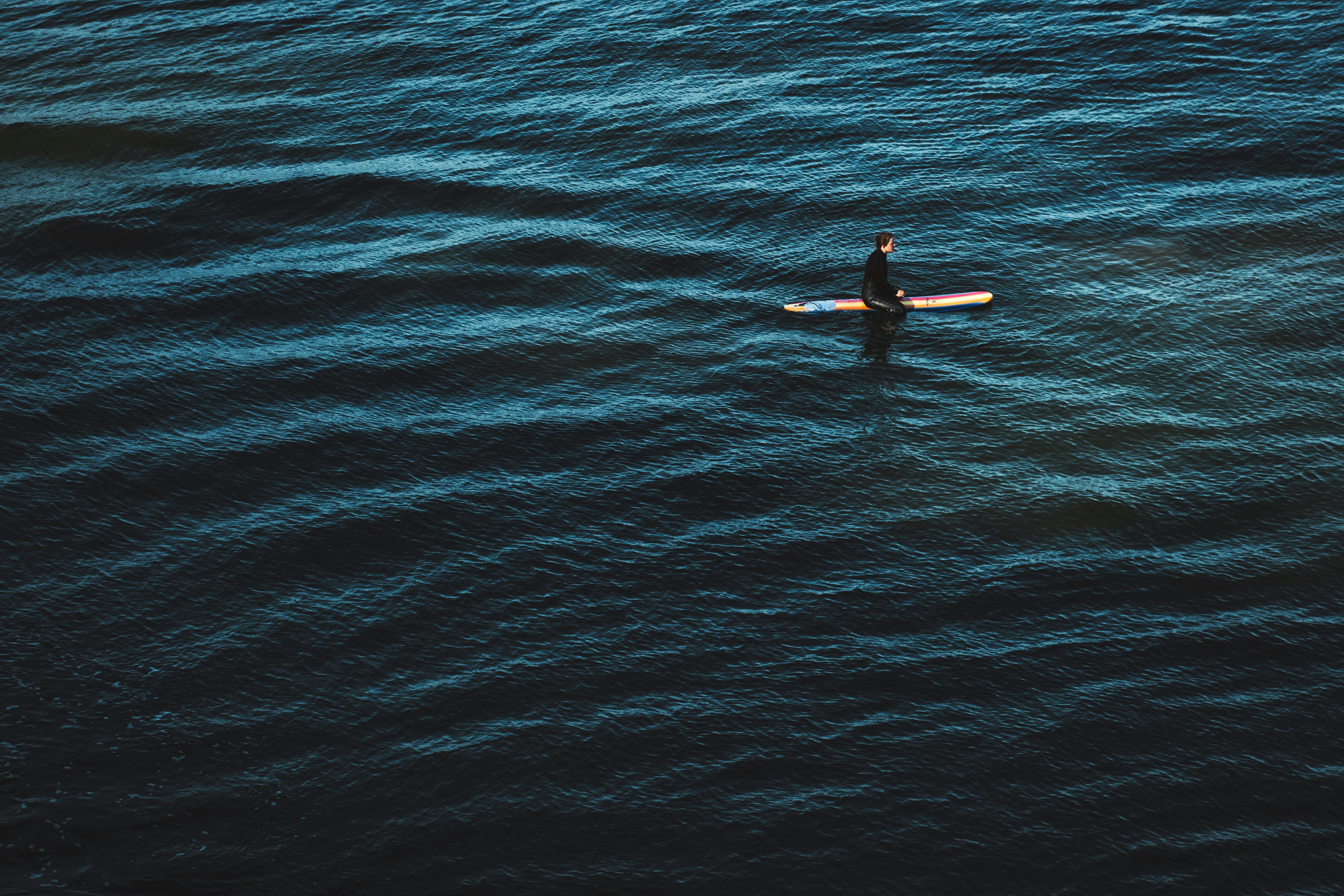 person in black wetsuit surfing on blue sea water during daytime